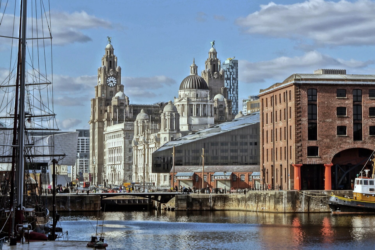 The Royal Liver Building and Pier Head waterfront seen across the Albert Dock, with brick warehouses on the right