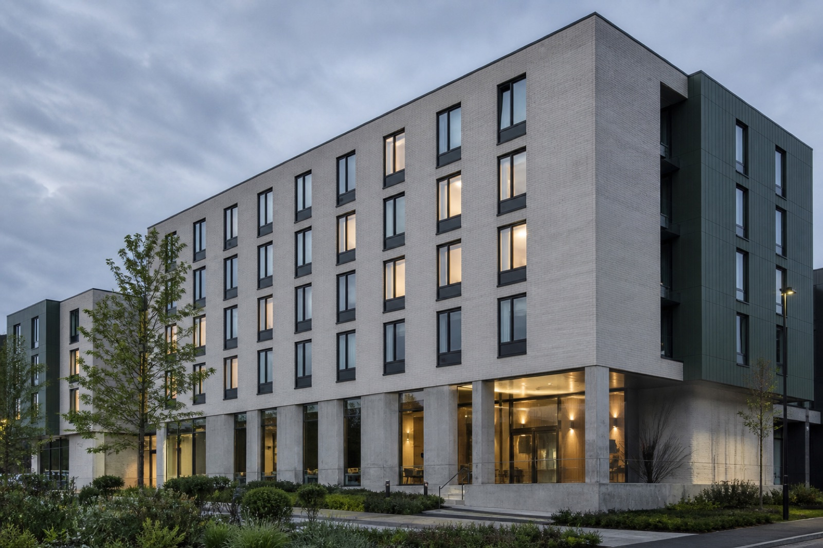 An operating student accommodation building in the evening with some windows lit